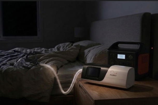 Close-up of a CPAP machine connected safely to a portable power station during a blackout in a bedroom.